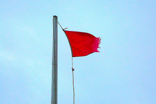 Rather tattered red flag flying on the clifftop at Porthleven
